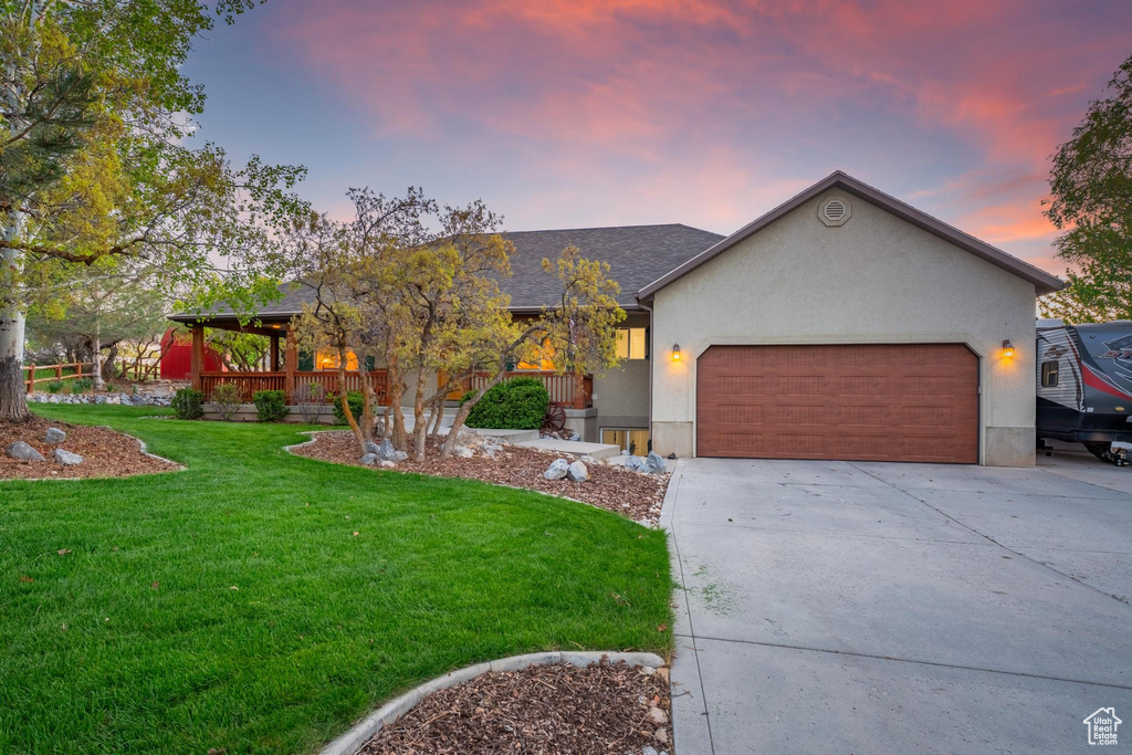 View of front of home featuring a lawn, an attached garage, stucco siding, and concrete driveway