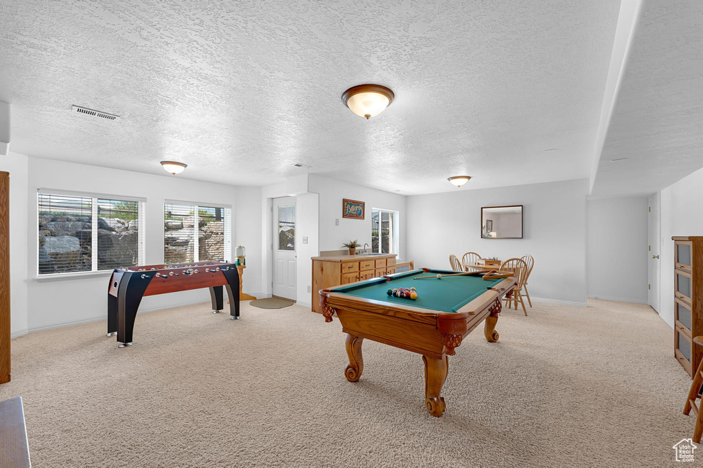 Game room with pool table, a textured ceiling, light carpet, and baseboards