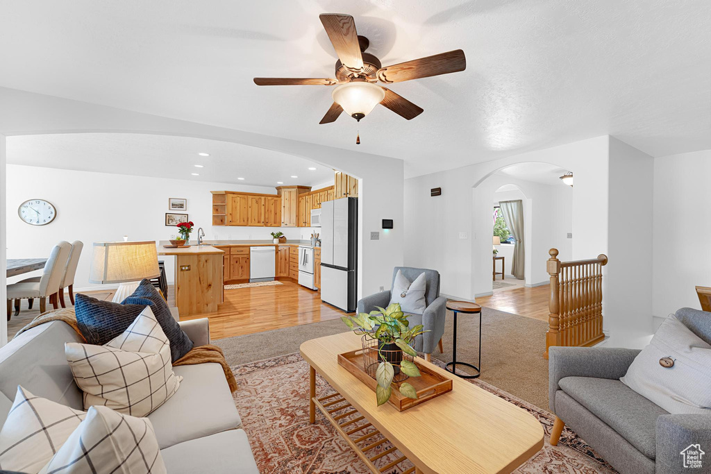 Living room featuring arched walkways, ceiling fan, recessed lighting, and light wood finished floors