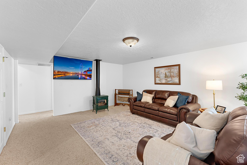 Carpeted living room with a textured ceiling, a wood stove, and baseboards