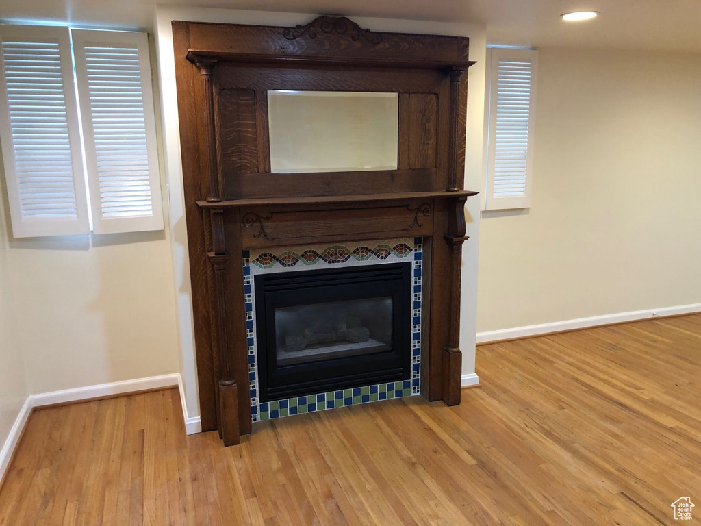Detailed view of baseboards, wood finished floors, a tiled fireplace, and recessed lighting