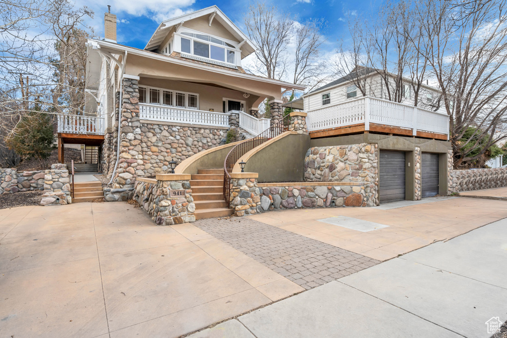 View of front of home with a chimney, stucco siding, driveway, stone siding, and a garage