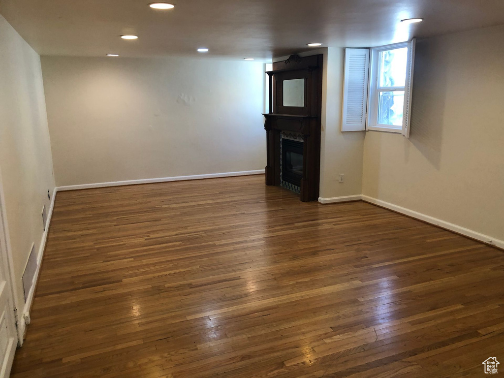 Unfurnished living room featuring dark wood finished floors, a fireplace, baseboards, and recessed lighting