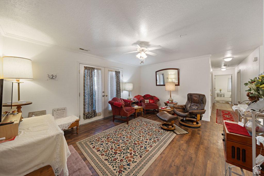 Living room featuring wood finished floors, ceiling fan, french doors, ornamental molding, and a textured ceiling