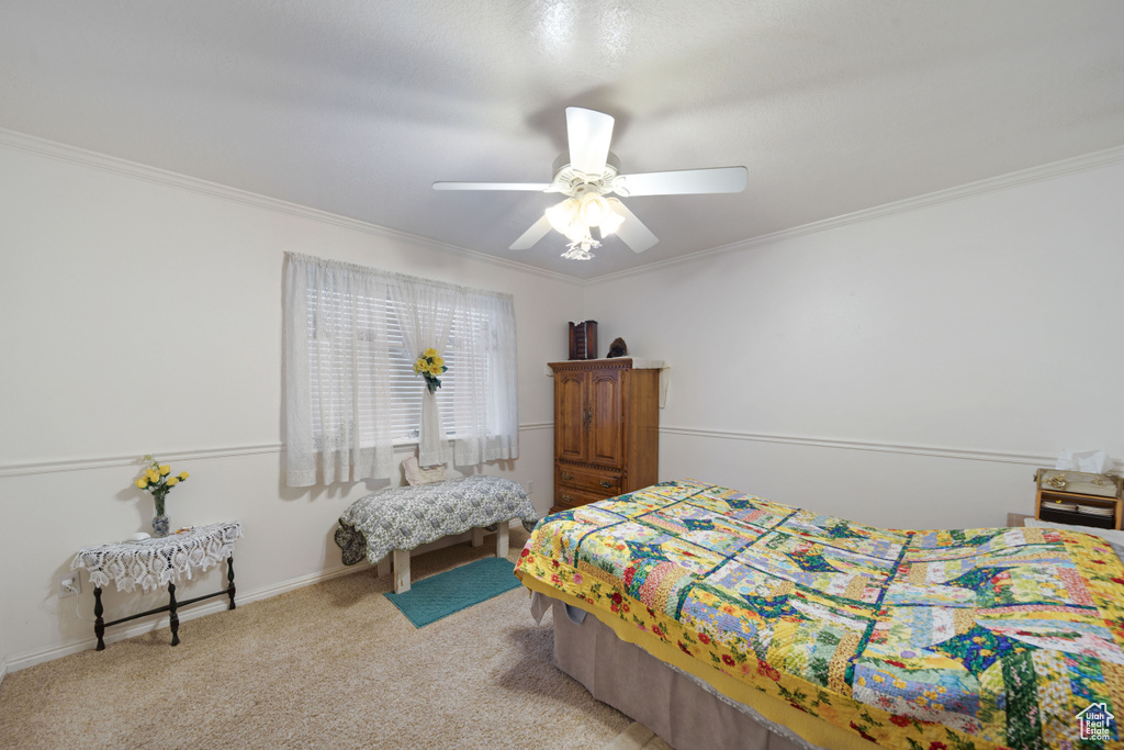 Carpeted bedroom featuring crown molding and ceiling fan