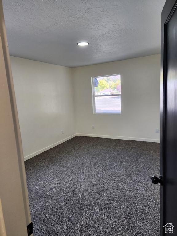 Spare room with dark carpet, baseboards, a textured ceiling, and recessed lighting