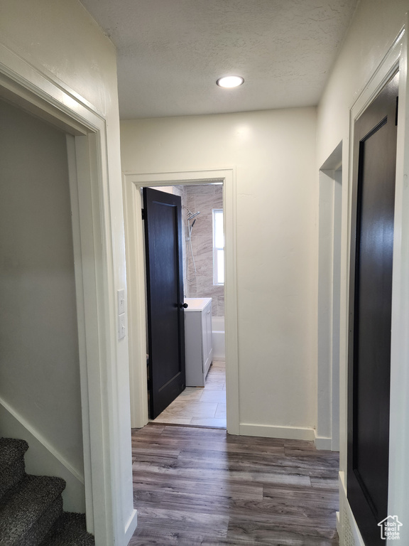 Hall with wood finished floors, a textured ceiling, stairway, and recessed lighting