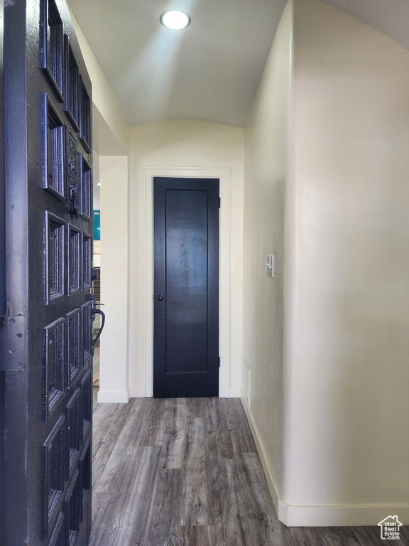 Doorway to outside featuring dark wood-style flooring, baseboards, and lofted ceiling