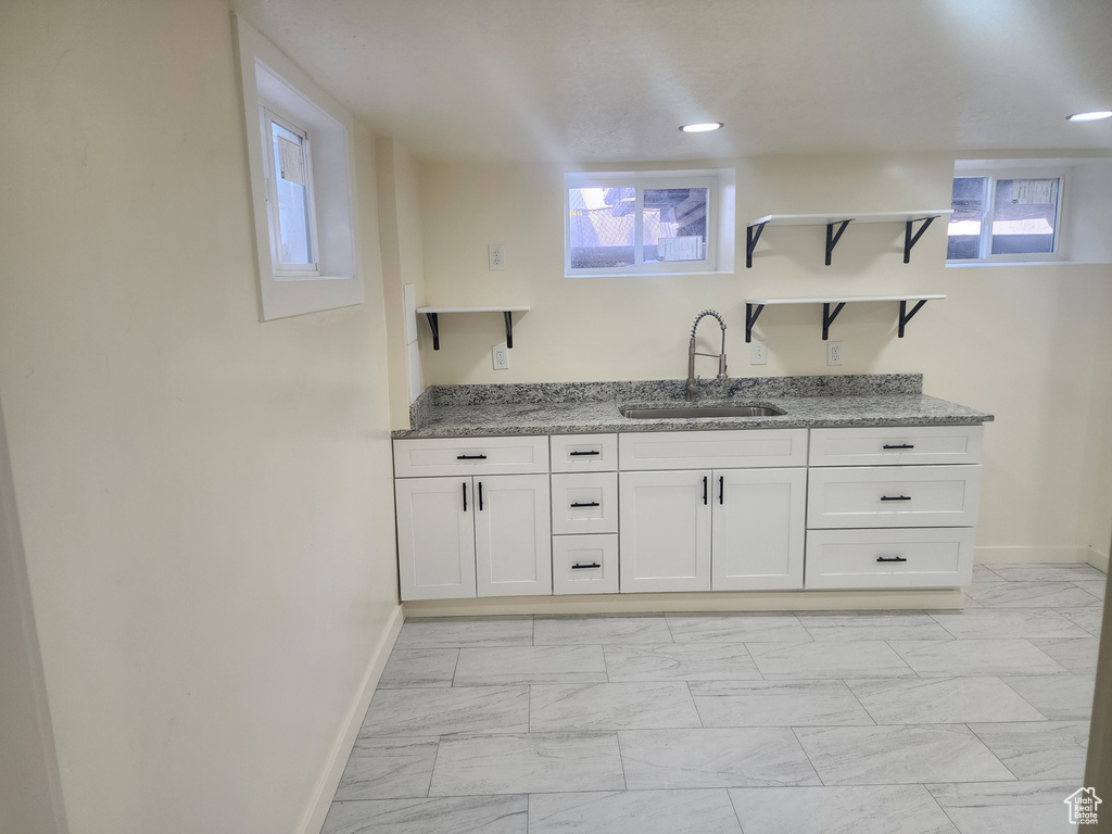 Bar with a sink, baseboards, and light marble finish flooring