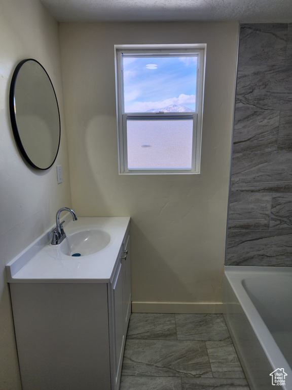 Full bath featuring baseboards, vanity, a tub, and marble finish flooring