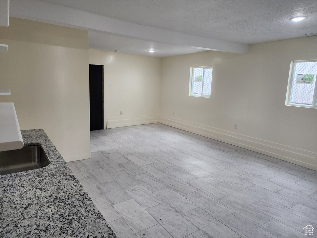 Unfurnished living room featuring a textured ceiling, baseboards, a sink, and recessed lighting