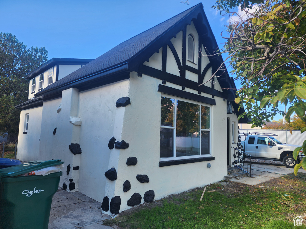 View of home's exterior featuring a shingled roof, fence, and stucco siding