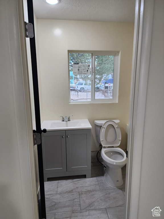 Bathroom with toilet, vanity, and marble finish flooring