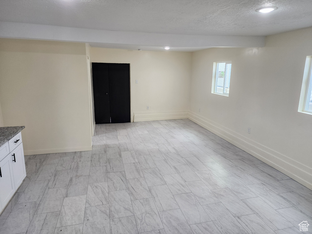 Spare room featuring a textured ceiling, baseboards, and recessed lighting