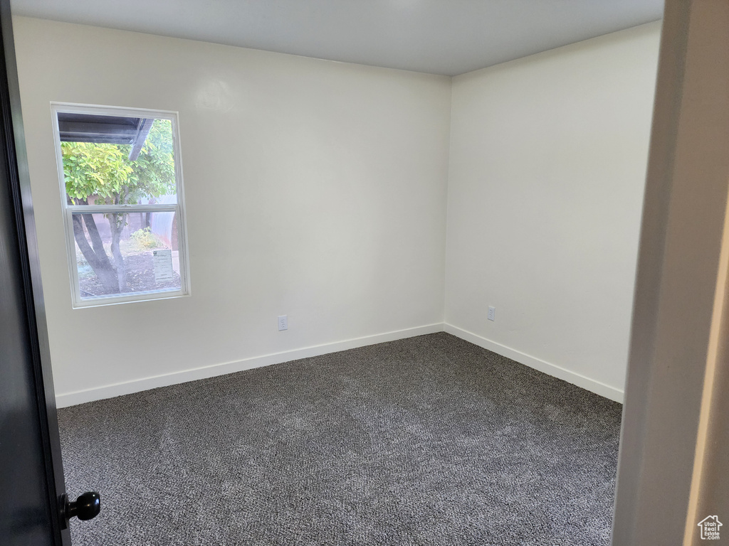 Spare room with dark colored carpet and baseboards