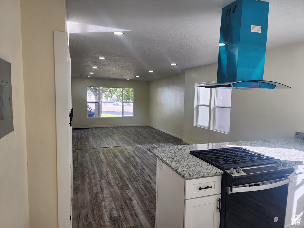 Kitchen with gas stove, island range hood, dark wood-type flooring, white cabinetry, and recessed lighting