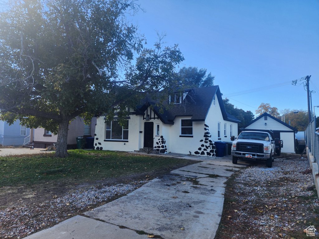 View of front of house with stucco siding, concrete driveway, a shingled roof, and an outbuilding