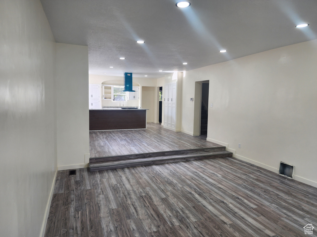 Unfurnished living room featuring wood finished floors, baseboards, and recessed lighting