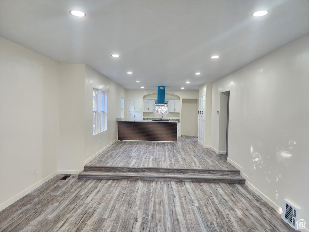 Unfurnished living room featuring light wood-type flooring, baseboards, recessed lighting, and a sink