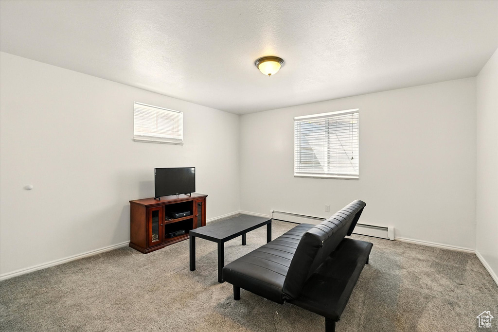 Living room featuring a baseboard heating unit, light carpet, and baseboards