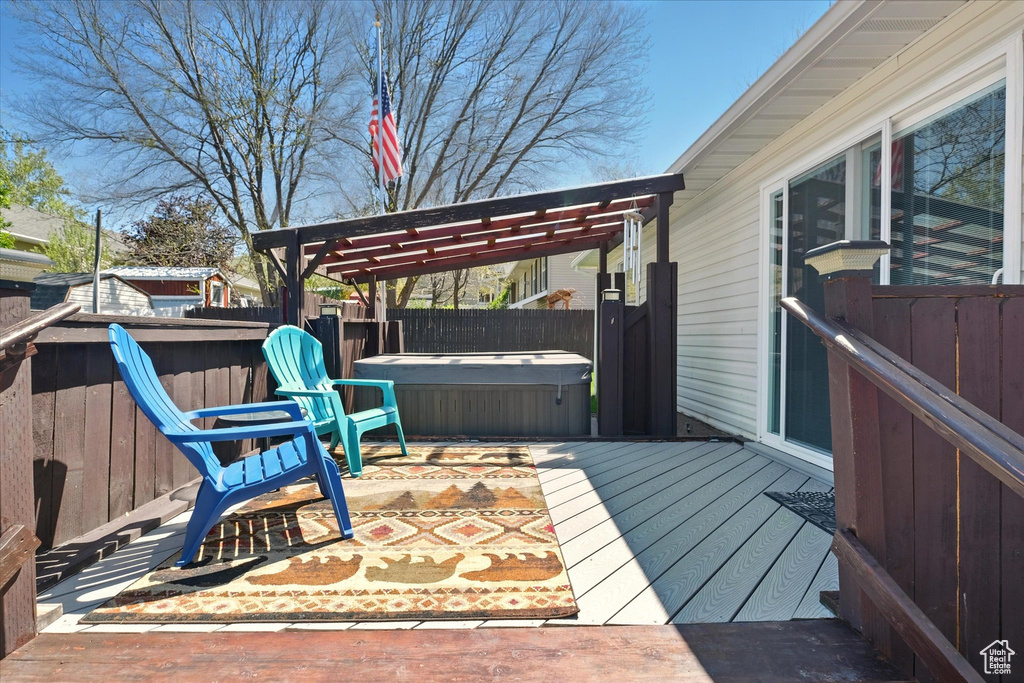 Wooden terrace featuring a hot tub, fence, and a pergola