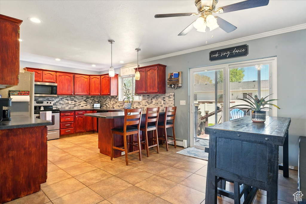 Kitchen with appliances with stainless steel finishes, reddish brown cabinets, dark countertops, backsplash, and ornamental molding