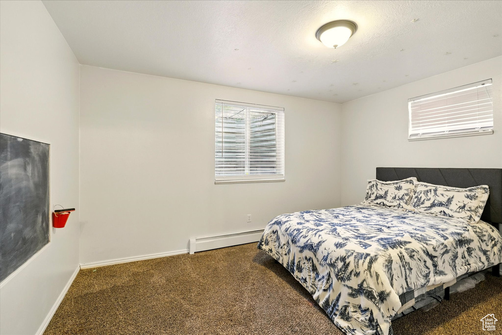 Carpeted bedroom featuring a baseboard radiator and baseboards