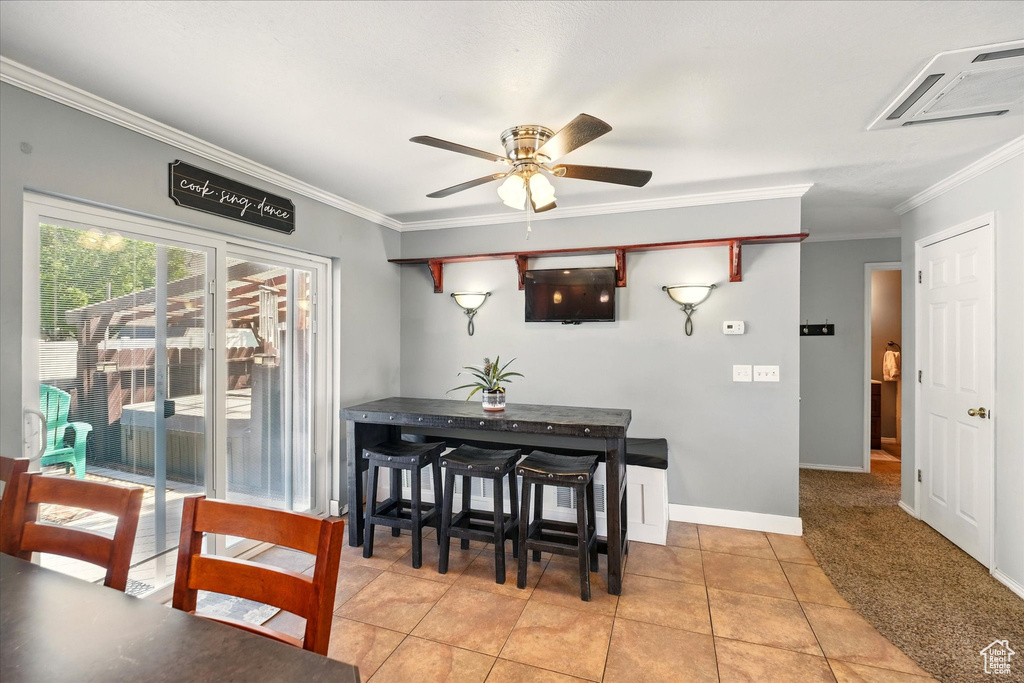 Dining area with crown molding, a ceiling fan, light tile patterned floors, and baseboards