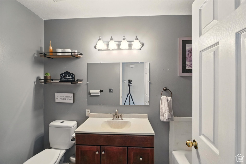 Bathroom featuring toilet, vanity, and a tub to relax in