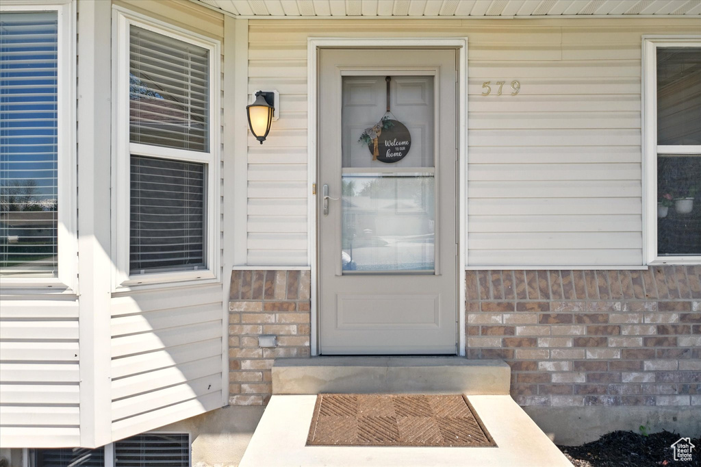 View of exterior entry featuring brick siding and a porch
