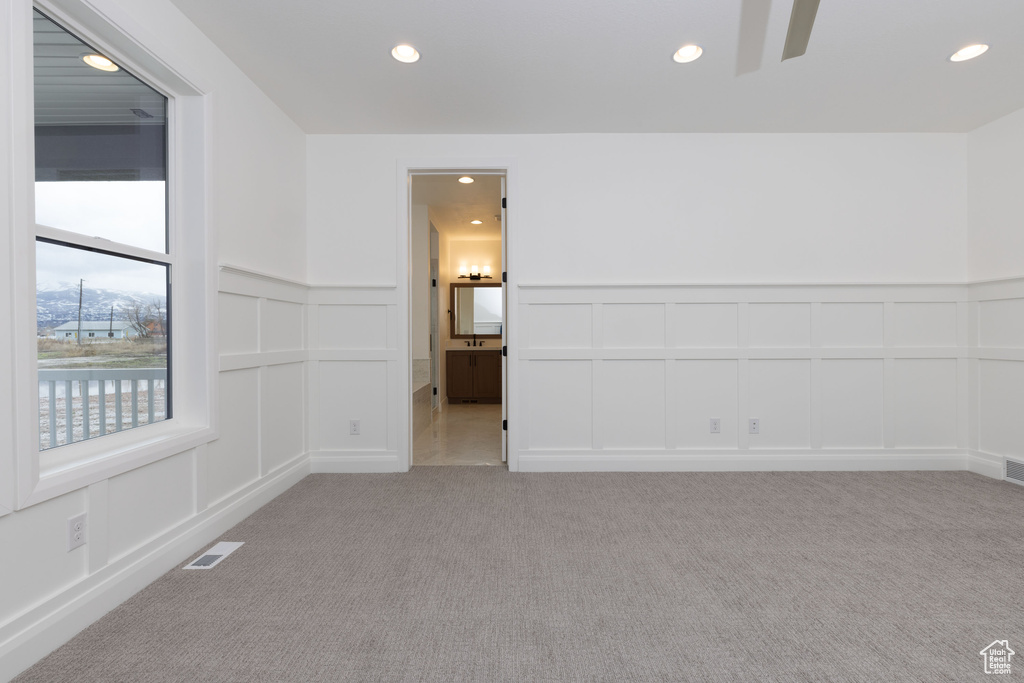 Empty room with a decorative wall, recessed lighting, light carpet, ceiling fan, and a wainscoted wall