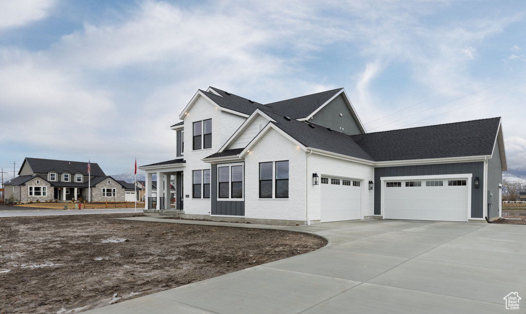 View of front of home featuring an attached garage, concrete driveway, brick siding, and roof with shingles
