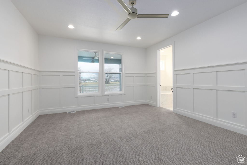 Carpeted spare room with a decorative wall, a ceiling fan, a wainscoted wall, and recessed lighting