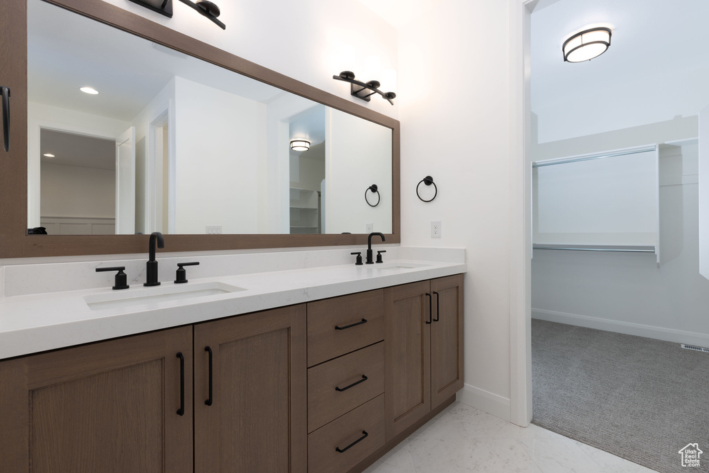 Full bathroom with double vanity, baseboards, a spacious closet, and recessed lighting