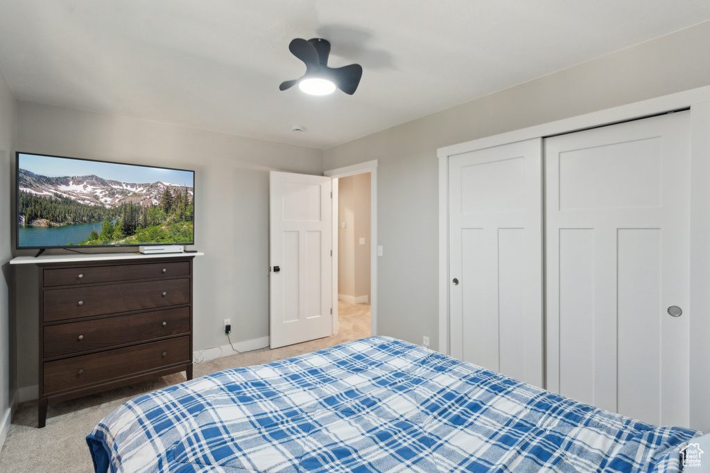 Bedroom featuring light colored carpet, baseboards, a closet, and a ceiling fan