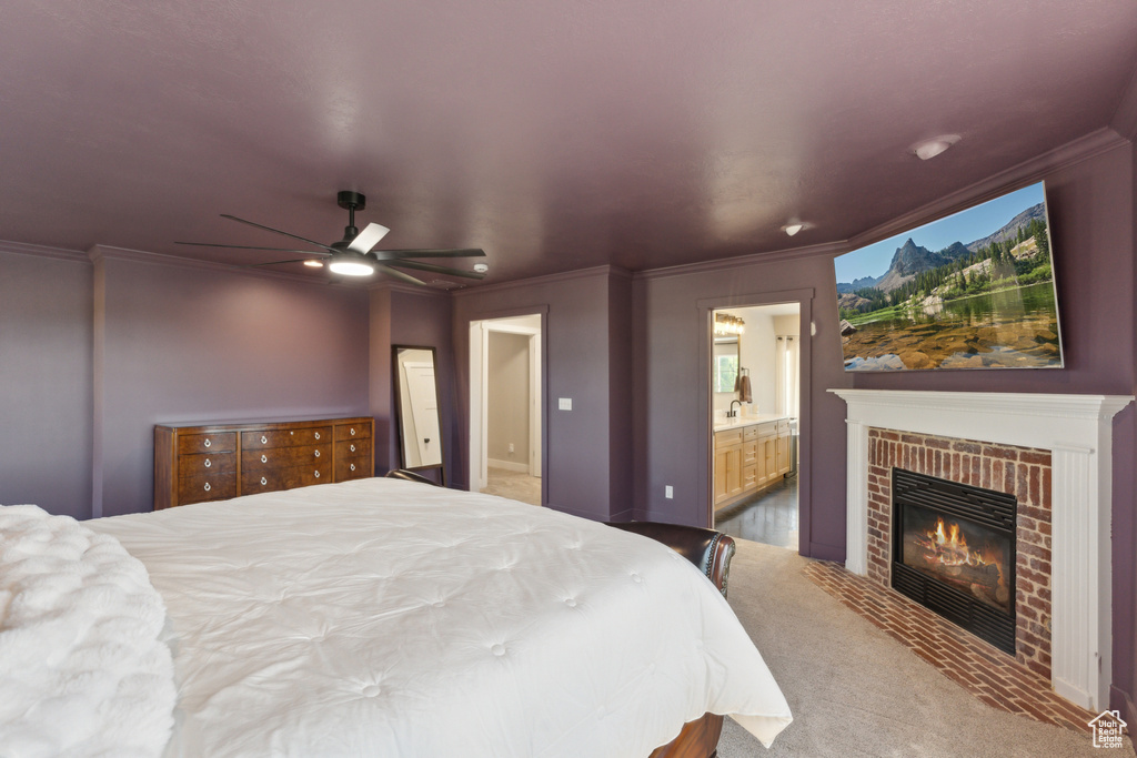 Bedroom with crown molding, a brick fireplace, ensuite bath, carpet floors, and a sink