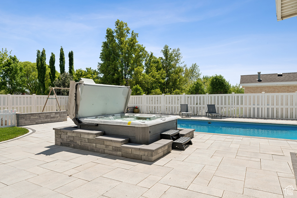 View of pool with a patio, a covered hot tub, and a fenced backyard