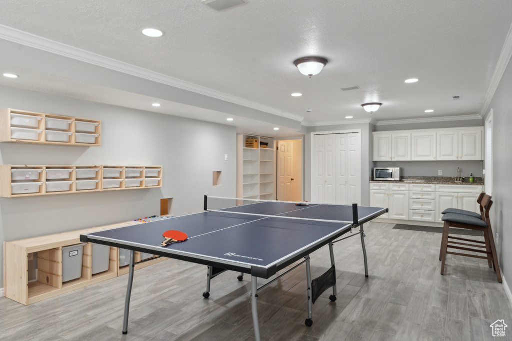 Playroom with ornamental molding, bar with sink, recessed lighting, light wood-style floors, and baseboards