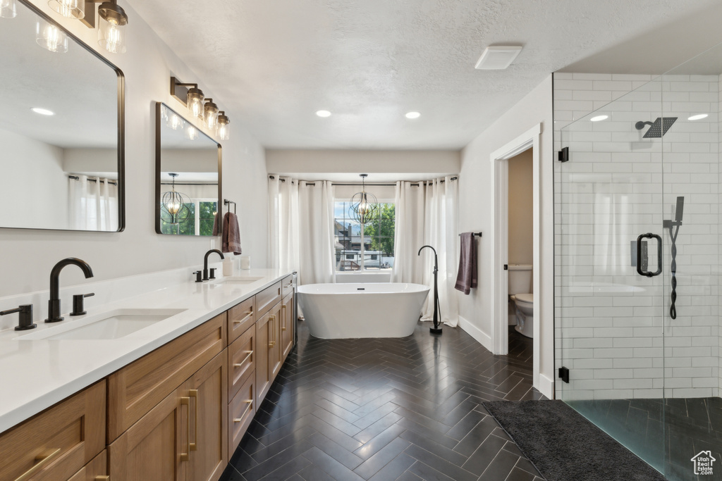 Full bath with a shower stall, double vanity, toilet, a freestanding bath, and recessed lighting