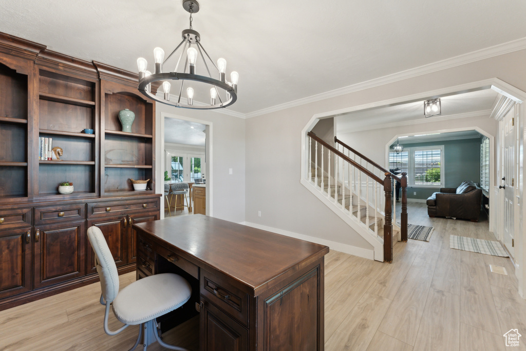 Home office featuring a chandelier, light wood-style flooring, baseboards, arched walkways, and ornamental molding