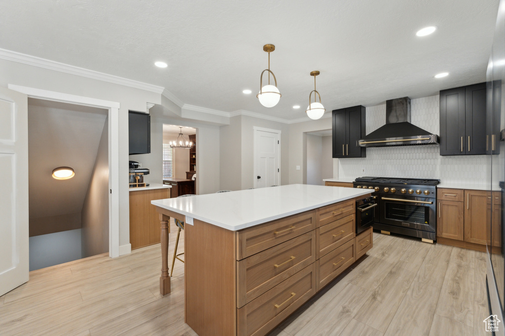 Kitchen with wall chimney range hood, high end stainless steel range, light wood-style floors, decorative backsplash, and a breakfast bar