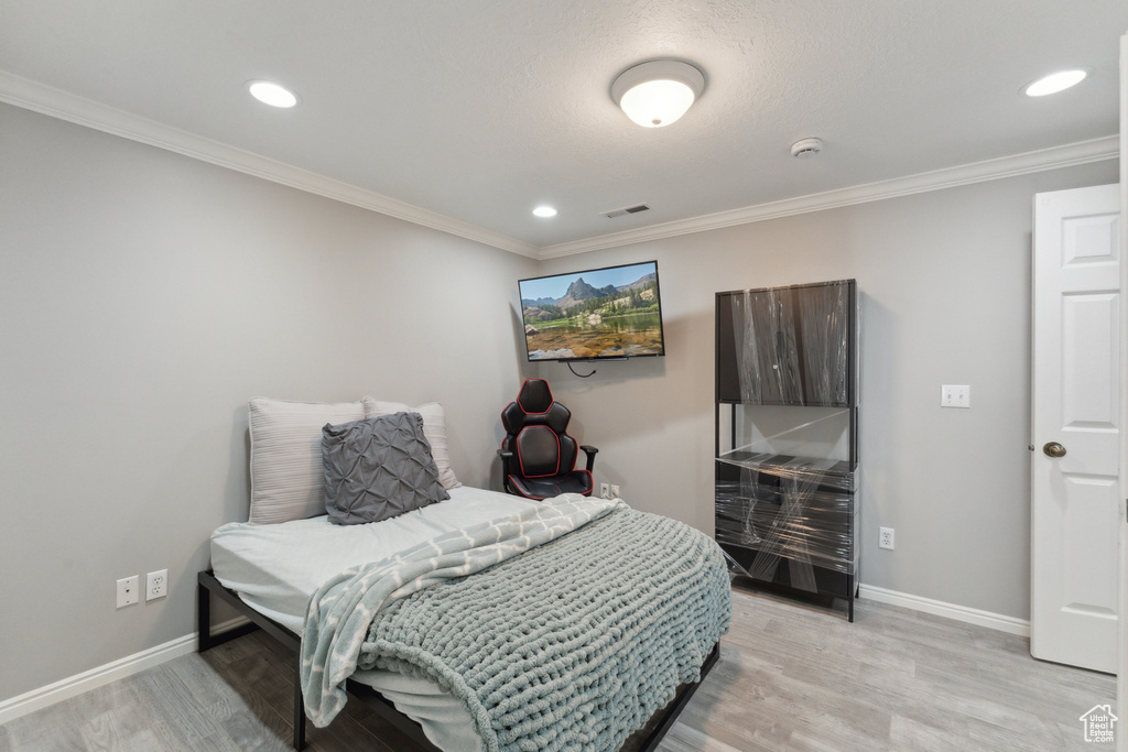 Bedroom featuring baseboards, light wood-style flooring, ornamental molding, and recessed lighting