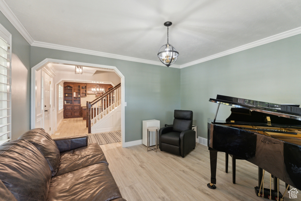 Living area featuring a chandelier, arched walkways, stairway, ornamental molding, and wood finished floors