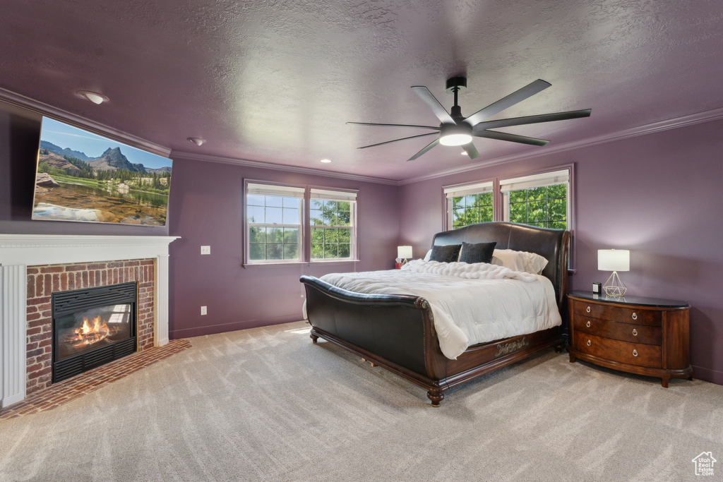 Bedroom featuring crown molding, carpet floors, a fireplace, baseboards, and ceiling fan
