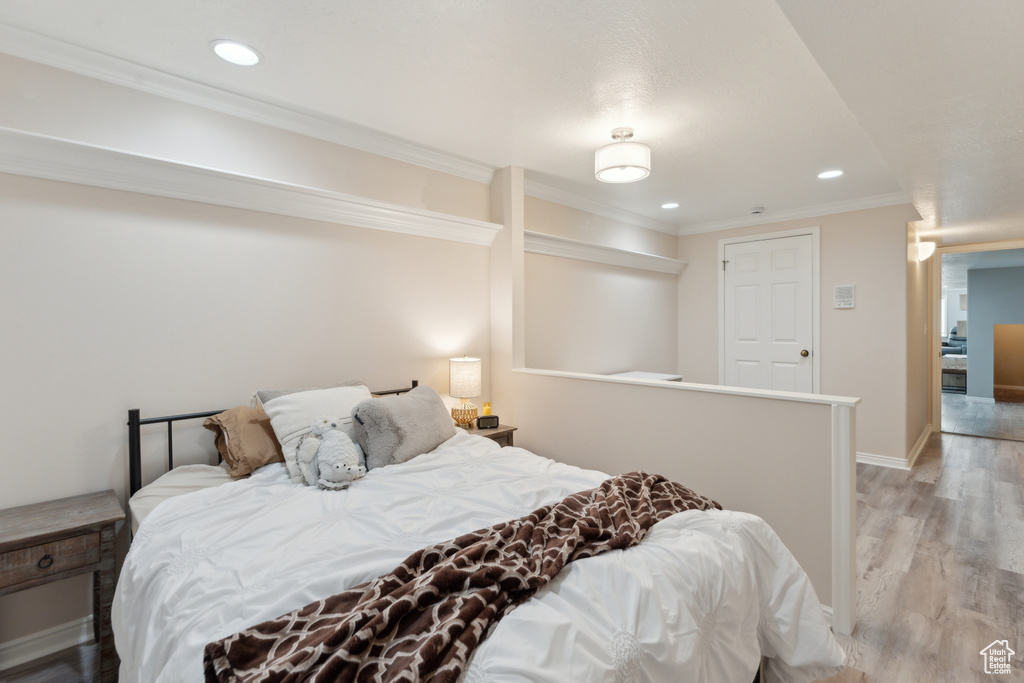 Bedroom with light wood-type flooring, recessed lighting, baseboards, and crown molding