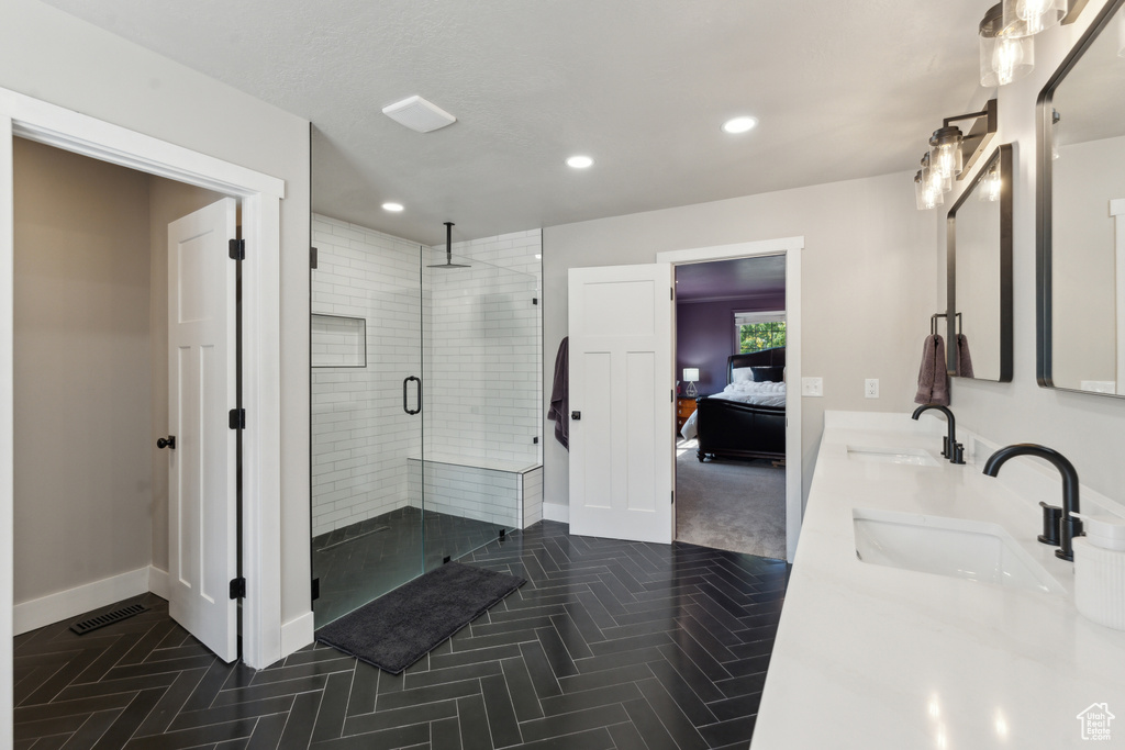 Ensuite bathroom featuring a stall shower, recessed lighting, baseboards, and double vanity