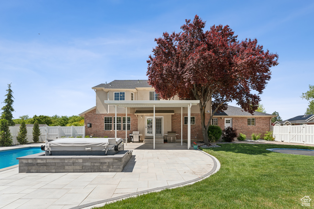 Back of house featuring a jacuzzi, french doors, a patio area, brick siding, and stucco siding