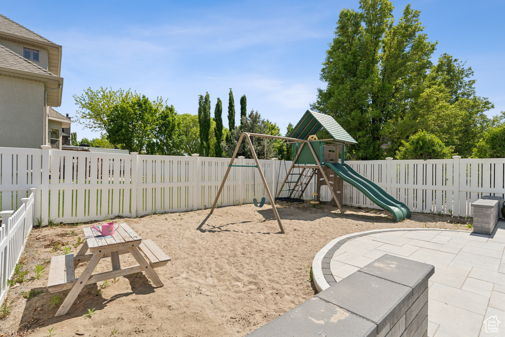 View of jungle gym featuring a fenced backyard and a patio