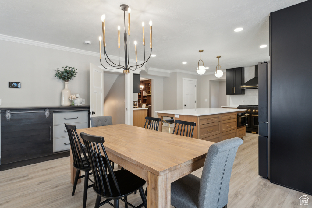 Dining area with light wood-style flooring, crown molding, recessed lighting, and a chandelier