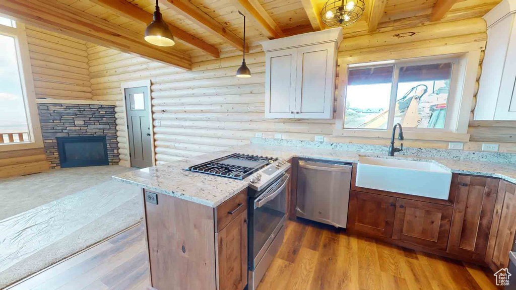Kitchen featuring appliances with stainless steel finishes, a sink, wood ceiling, log walls, and beam ceiling